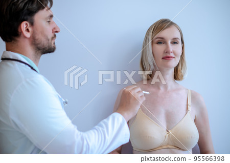 Experienced plastic surgeon preparing a woman for plastic surgery 95566398