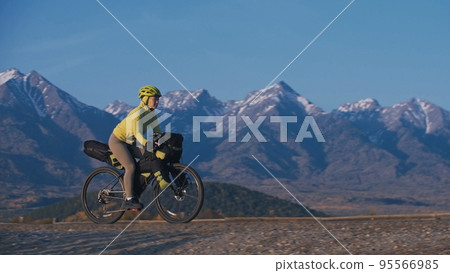 The woman travel on mixed terrain cycle touring with bikepacking. The traveler journey with bicycle bags. Sport tourism bikepacking. The woman travel on mixed terrain cycle touring with bikepacking. The traveler journey with bicycle bags. Sport tourism bikepacking. 95566985