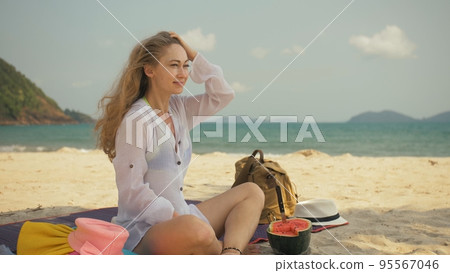 The cheerful woman in holding and eating slices of watermelon on tropical sand beach sea. Portrait attractive girl spend summer weekend. The cheerful woman in holding and eating slices of watermelon on tropical sand beach sea. Portrait attractive girl spend summer weekend. 95567046