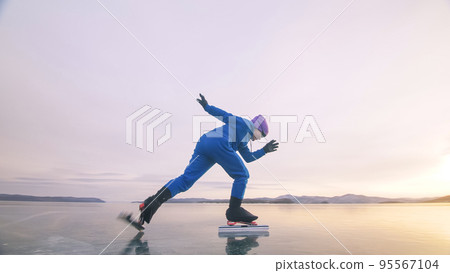 The child train on ice professional speed skating. The girl skates in the winter in sportswear, sport glasses, suit. Outdoor slow motion. 95567104