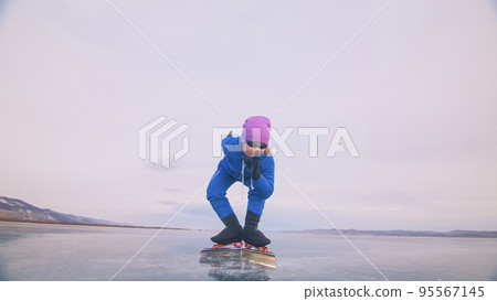 The child train on ice speed skating. The athlete at the start, in a sports stance. The kid girl skates in the winter in sportswear, sport glasses. The child train on ice speed skating. The athlete at the start, in a sports stance. The kid girl skates in the winter in sportswear, sport glasses. 95567145