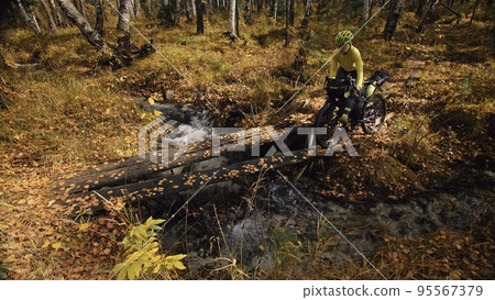 The woman travel on mixed terrain cycle touring with bikepacking. The traveler journey with bicycle bags. Sport tourism bikepacking. The woman travel on mixed terrain cycle touring with bikepacking. The traveler journey with bicycle bags. Sport tourism bikepacking. 95567379