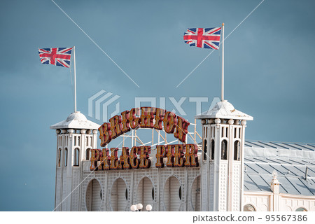 Brighton Palace Pier, with the seafront behind. View of the stunning city of Brighton and Hove with seagulls flying around at sunset. 95567386