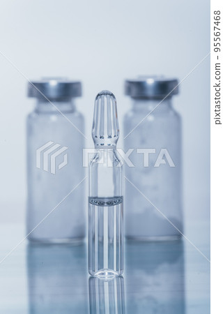 Glass medical ampoule vial for injection. Medicine is liquid sodium chloride with of aqueous solution in ampulla. Close up. Bottles ampule multicolor. 95567468