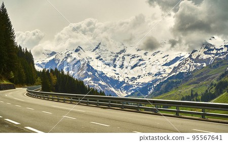 Cloudy Dachstein mountains in Austria with the high alpine road in the foreground during a road trip through the Alps Cloudy Dachstein mountains in Austria with the high alpine road in the foreground during a road trip through the Alps 95567641