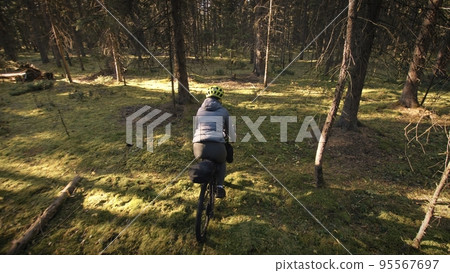 The woman travel on mixed terrain cycle touring with bike bikepacking. The traveler journey with bicycle bags. Magic forest park. 95567697