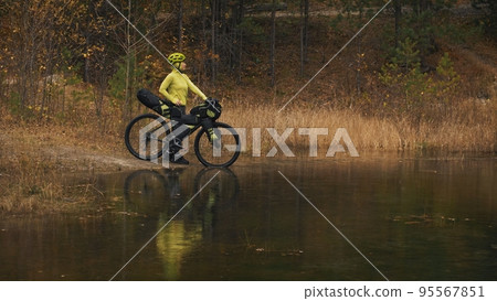 The woman travel on mixed terrain cycle touring with bikepacking. The traveler journey with bicycle bags. Sport tourism bikepacking. 95567851
