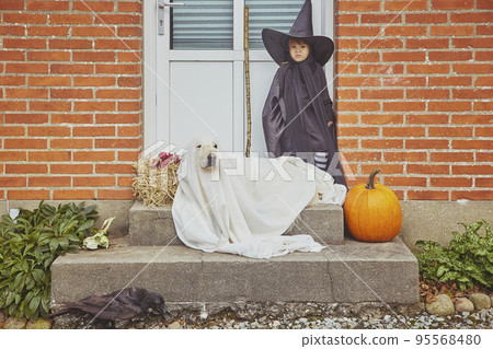 Adorable sad child with dog on porch dressed in halloween costumes Adorable sad child with dog on porch dressed in halloween costumes 95568480