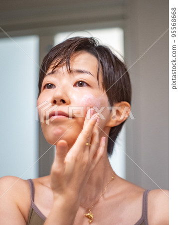 一個女人洗完澡後在鏡子前做皮膚護理 一個女人洗完澡後在鏡子前做皮膚護理 95568668