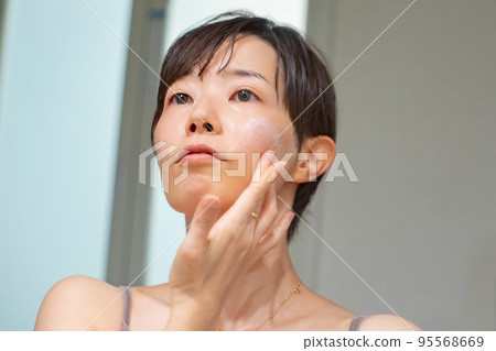 一個女人洗完澡後在鏡子前做皮膚護理 一個女人洗完澡後在鏡子前做皮膚護理 95568669