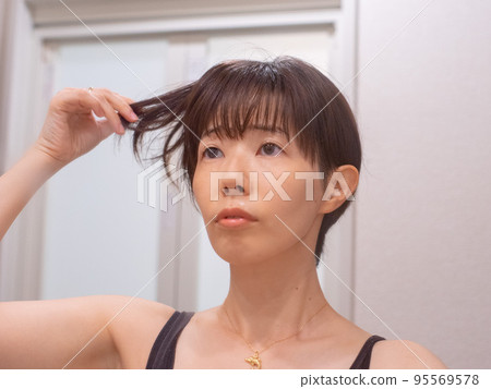 A woman who cares about her hair in front of the mirror A woman who cares about her hair in front of the mirror 95569578