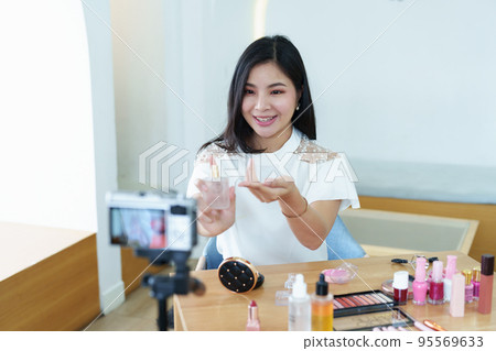online trading business, a beautiful young woman working independently at home reviewing cosmetic products through the camera to customers to increase their interest in making a purchase decision. 95569633