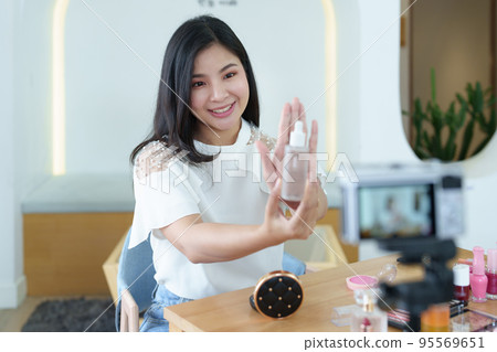 online trading business, a beautiful young woman working independently at home reviewing cosmetic products through the camera to customers to increase their interest in making a purchase decision. online trading business, a beautiful young woman working independently at home reviewing cosmetic products through the camera to customers to increase their interest in making a purchase decision. 95569651