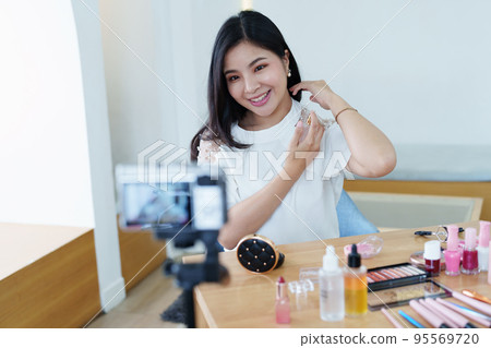 online trading business, a beautiful young woman working independently at home reviewing cosmetic products through the camera to customers to increase their interest in making a purchase decision. 95569720