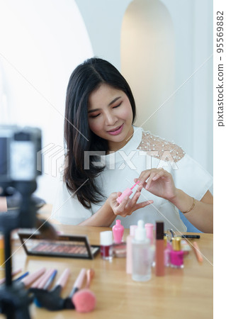 online trading business, a beautiful young woman working independently at home reviewing cosmetic products through the camera to customers to increase their interest in making a purchase decision. online trading business, a beautiful young woman working independently at home reviewing cosmetic products through the camera to customers to increase their interest in making a purchase decision. 95569882