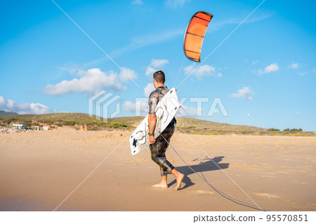 Portrait wave kitesurfer walking beach with his board and kite Portrait wave kitesurfer walking beach with his board and kite 95570851