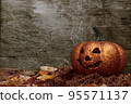 Glittering Halloween pumpkin in autumn leaves on wooden background 95571137