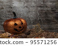 Glittering pumpkin in autumn leaves on wooden desk. Halloween background 95571256