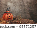 Funny pumpkin in autumn leaves on wooden desk. Halloween background 95571257