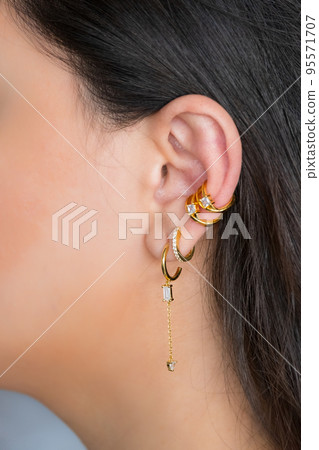 Woman ear with mulriple piercings wearing beautiful earrings with zirconia.  Beautiful valentine's gift. 95571707
