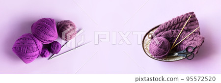 A purple ball of thread and a knitted hat with knitting needles and scissors in a basket on a purple background, banner A purple ball of thread and a knitted hat with knitting needles and scissors in a basket on a purple background, banner 95572520
