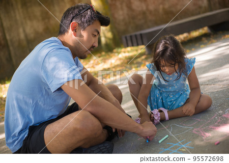 Portrait of Asian dad and daughter drawing together in park 95572698