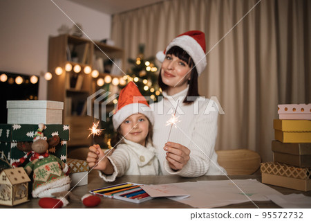 Focus on hands with sparkles, blur background of cheerful girl and her mother with charming smile 95572732