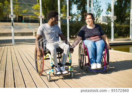 Tender man and woman in wheelchairs spending time near water Tender man and woman in wheelchairs spending time near water 95572860