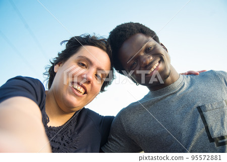 Contented biracial couple taking selfie on embankment 95572881