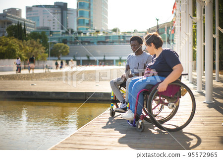 Man and woman in wheelchairs spending time near water 95572965