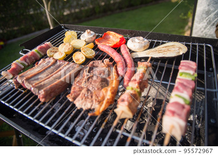 Tasty BBQ food cooking on summer day 95572967