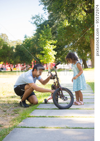 Portrait of Asian dad and nice girl repairing small bike in park 95572974