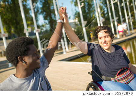 Jolly man and woman in wheelchairs spending time near water 95572979