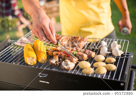 Close-up of man grilling meat and vegetables on sunny day Close-up of man grilling meat and vegetables on sunny day 95572980