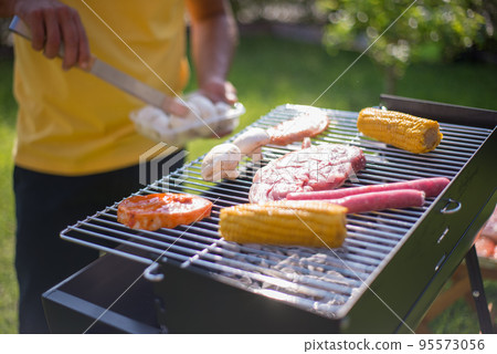 Close-up of steak, sausages and vegetables on BBQ 95573056