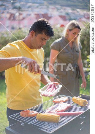 Concentrated mid adult man grilling steak and corn 95573057
