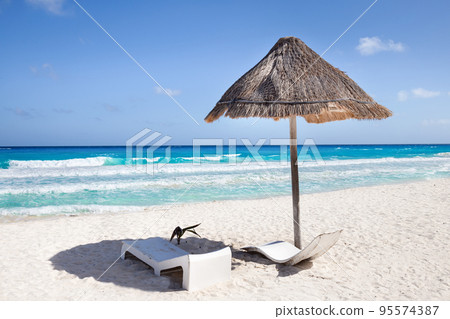 Sun umbrella ans sunbed on white sandy beach with turquoise ocean water. Caribbean sea travel destination. Bounty and pristine nature for vacation Sun umbrella ans sunbed on white sandy beach with turquoise ocean water. Caribbean sea travel destination. Bounty and pristine nature for vacation 95574387
