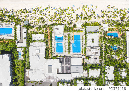 Outdoor poolside with swimming pools, coconut palm trees near sandy tropical beach. Caribbean travel. Aerial top view 95574418