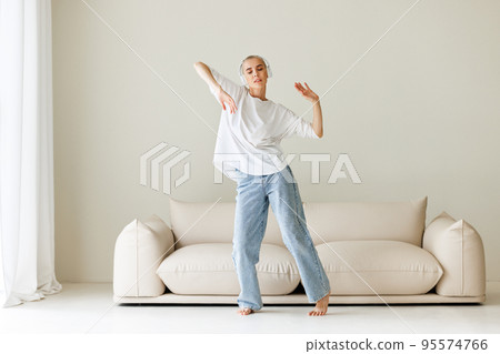 Beautiful woman meloman with very short hair dancing near couch Beautiful woman meloman with very short hair dancing near couch 95574766