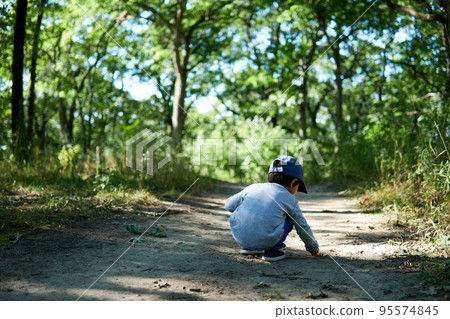 一個男孩蹲在森林裡的一條人行道上，擔心土壤 95574845