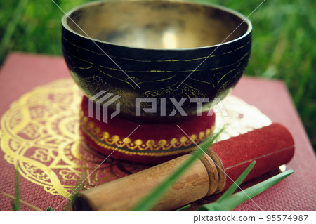 Tibetan bowl with a stick on the grass 95574987