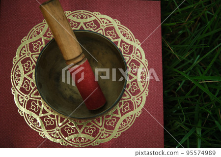 Tibetan bowl with a stick on the grass 95574989
