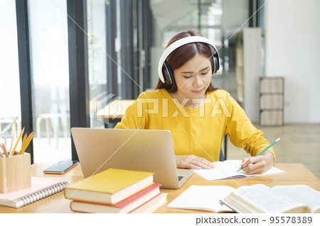 Woman learning online using laptop and writing notes. Woman learning online using laptop and writing notes. 95578389