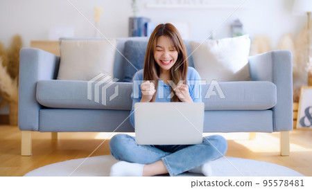 Young asian woman in good spirits working on laptop at home Young asian woman in good spirits working on laptop at home 95578481