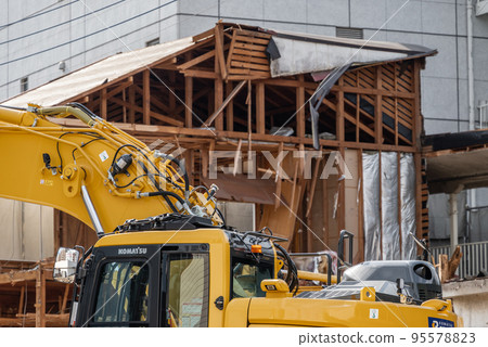 Heavy machinery demolishing a wooden apartment building Heavy machinery demolishing a wooden apartment building 95578823