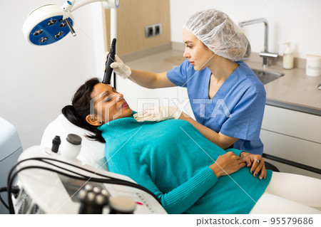Beautician doing needle-free mesotherapy for hispanic woman Beautician doing needle-free mesotherapy for hispanic woman 95579686