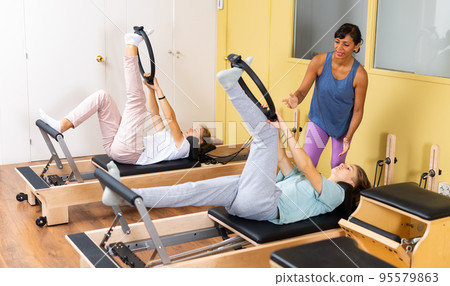 Teens doing pilates exercises with trainer 95579863