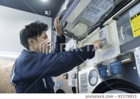 A worker man who maintains a coin laundry A worker man who maintains a coin laundry 95579953