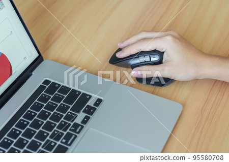 woman hand using ergonomic vertical mouse during working on Adjustable desk, prevention wrist pain. De Quervain s tenosynovitis, Intersection Symptom, Carpal Tunnel or Office syndrome concept 95580708