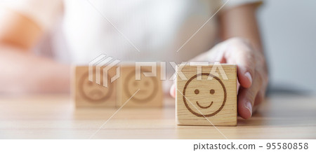 Hand choosing smile face from Emotion block for customer review, good experience, positive feedback, satisfaction, survey, evaluation, assessment, mood, world mental health day concept 95580858